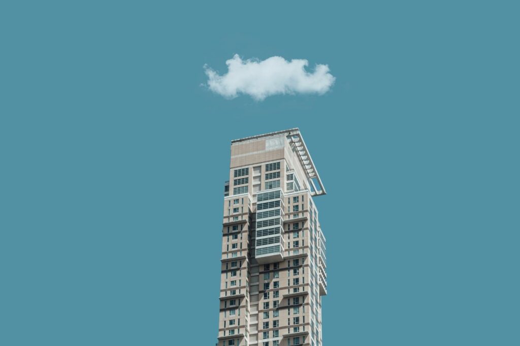 Mastering the First Impression: Your intriguing post title goes here Low-angle shot of a modern high-rise building against a clear sky with a single cloud above.