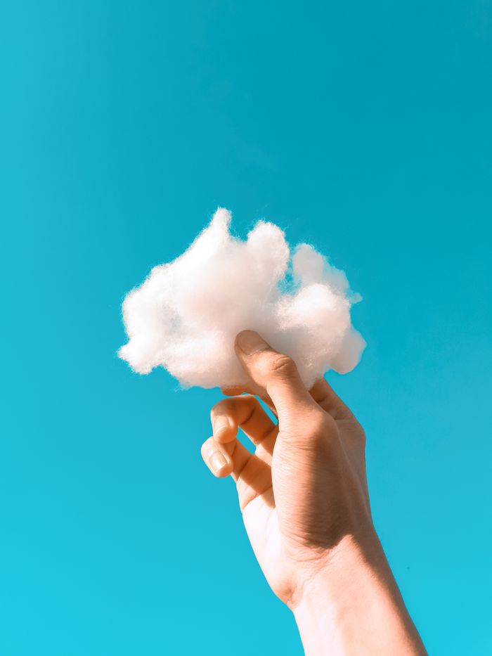 The Art of Drawing Readers In: Your attractive post title goes here A hand holding a fluffy cotton-like cloud against a bright blue clear sky.